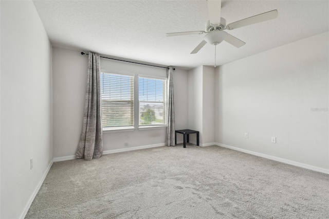 empty room featuring carpet floors, a ceiling fan, baseboards, and a textured ceiling