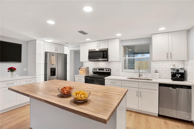 kitchen with visible vents, appliances with stainless steel finishes, white cabinetry, wooden counters, and a sink