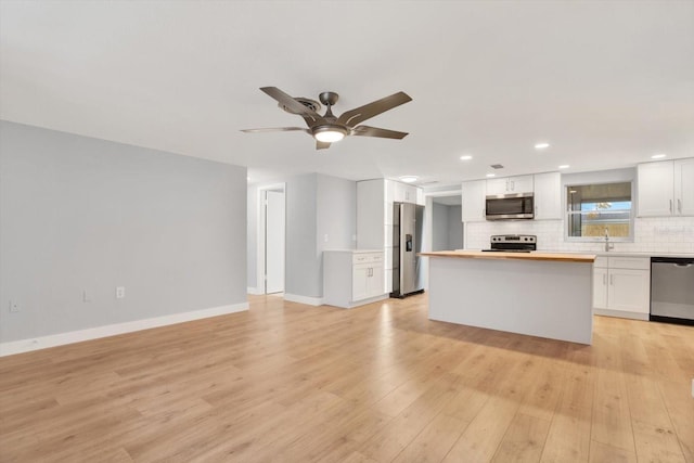 kitchen featuring decorative backsplash, appliances with stainless steel finishes, white cabinetry, butcher block countertops, and light wood-type flooring