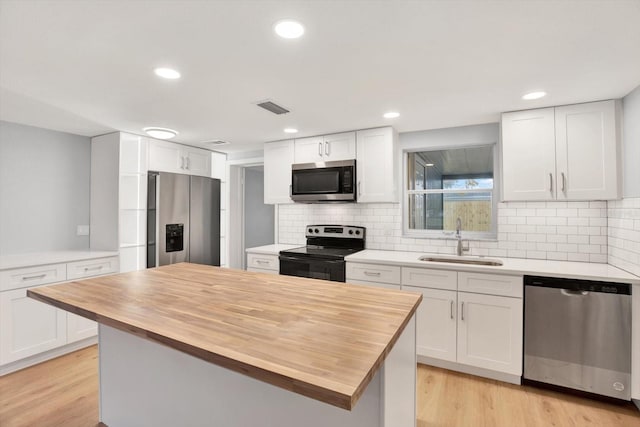 kitchen featuring stainless steel appliances, visible vents, light wood-style flooring, a sink, and wood counters