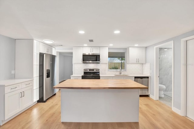 kitchen featuring white cabinetry, wood counters, appliances with stainless steel finishes, and tasteful backsplash