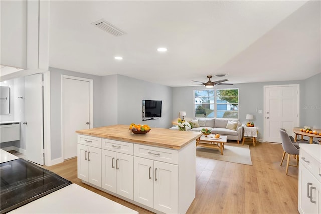 kitchen featuring butcher block counters, visible vents, light wood finished floors, and white cabinets