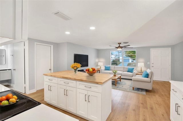 kitchen featuring light wood finished floors, white cabinetry, visible vents, and wooden counters