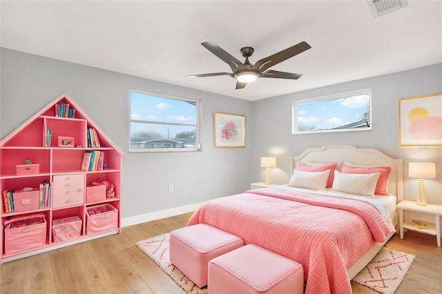 bedroom featuring baseboards, multiple windows, visible vents, and wood finished floors