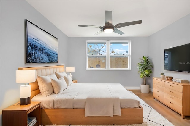 bedroom featuring a ceiling fan, baseboards, and light wood finished floors