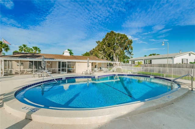 community pool with a patio area, fence, and a sunroom