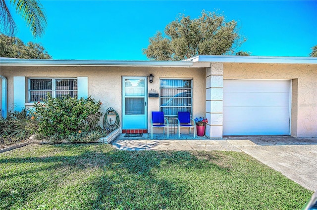 view of front of house featuring a garage, concrete driveway, a front lawn, and stucco siding