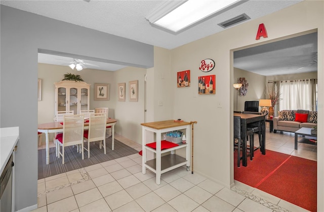 dining area with light tile patterned floors, ceiling fan, visible vents, and a textured ceiling