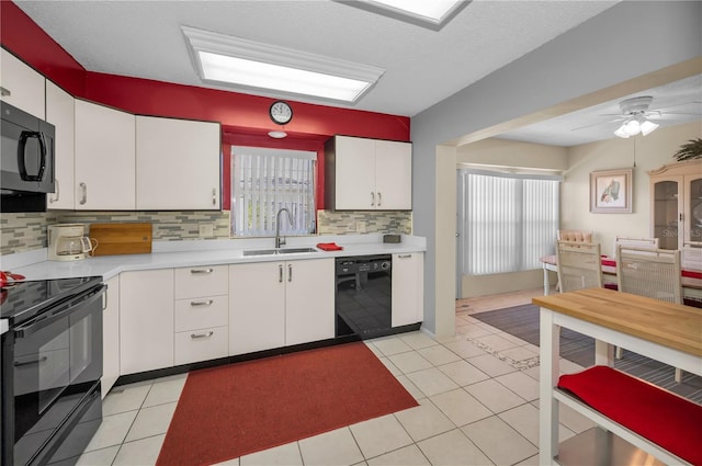 kitchen with light countertops, white cabinets, a sink, light tile patterned flooring, and black appliances