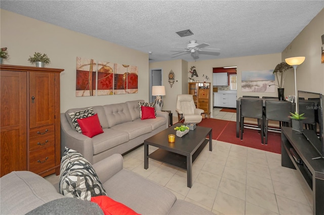 living area featuring a ceiling fan, visible vents, a textured ceiling, and light tile patterned floors