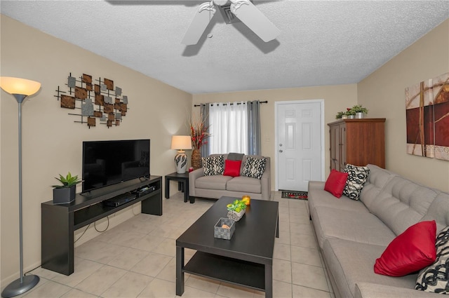 living area with a ceiling fan, light tile patterned flooring, and a textured ceiling