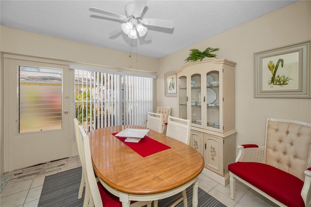 dining area with a ceiling fan, a textured ceiling, and light tile patterned flooring