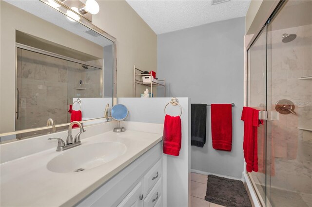 full bathroom with tile patterned floors, a shower stall, a textured ceiling, and vanity