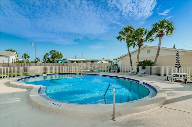 pool with a patio area and fence