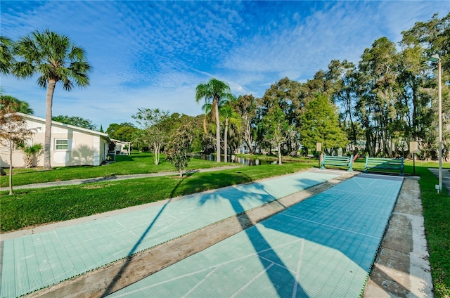 view of community with shuffleboard and a yard