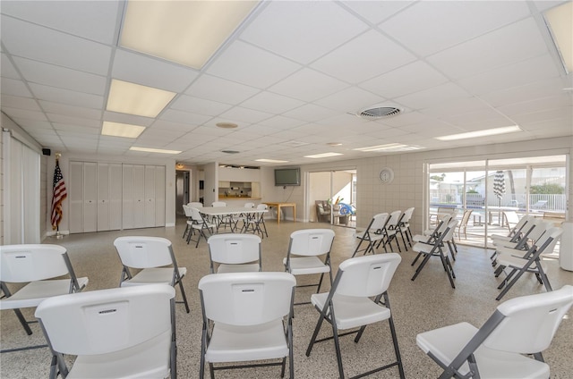 interior space featuring visible vents, a drop ceiling, and speckled floor