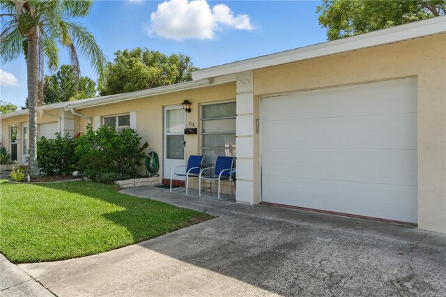 858 Cambridge Ct Unit 858, Dunedin, FL 34698 - view of front of property with stucco siding, a front yard, driveway, and a garage