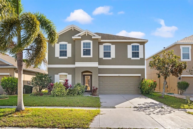 view of front of home featuring stucco siding, a front yard, concrete driveway, and an attached garage