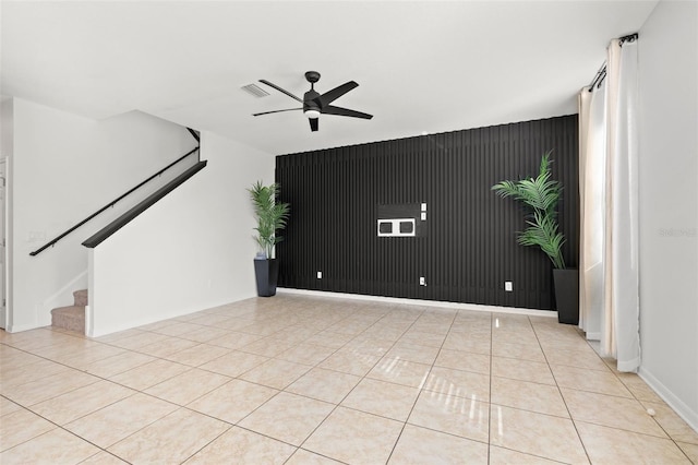 tiled spare room with visible vents, an accent wall, baseboards, ceiling fan, and stairs