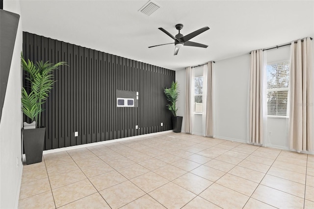 tiled spare room featuring plenty of natural light, baseboards, visible vents, and ceiling fan