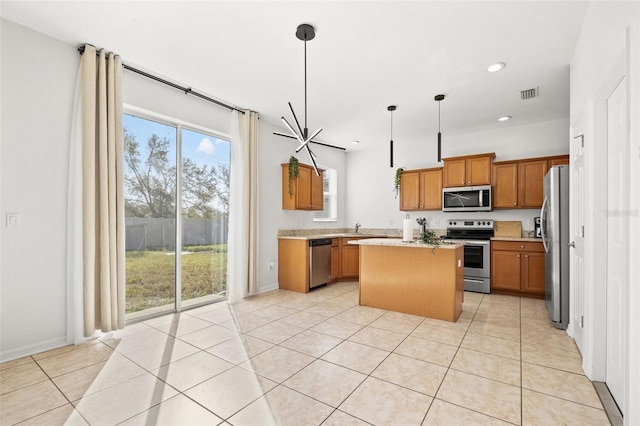 kitchen with visible vents, brown cabinets, a center island, appliances with stainless steel finishes, and light countertops