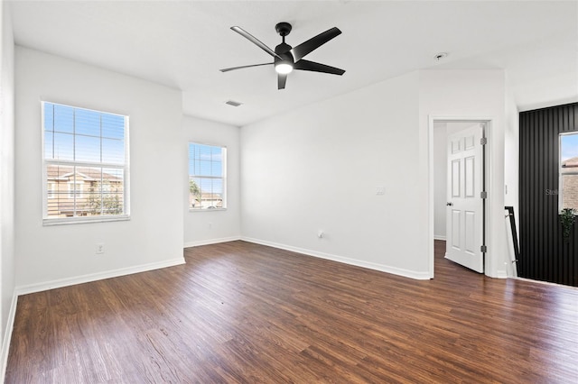 unfurnished room with a wealth of natural light, visible vents, wood finished floors, and a ceiling fan