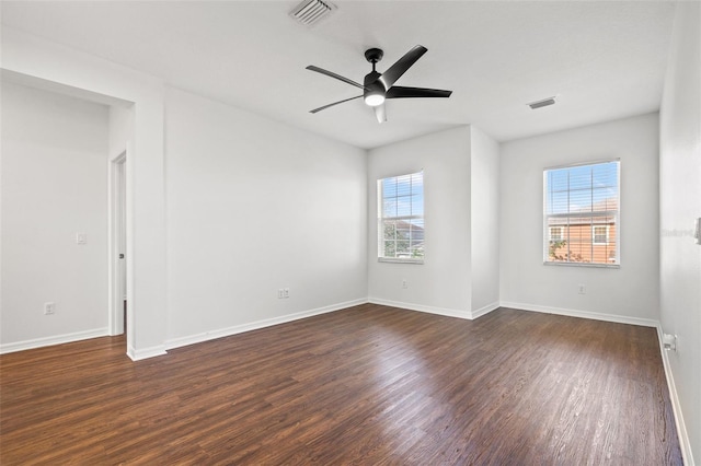 empty room featuring dark wood finished floors, baseboards, and visible vents