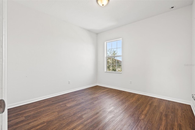 empty room with dark wood-type flooring and baseboards