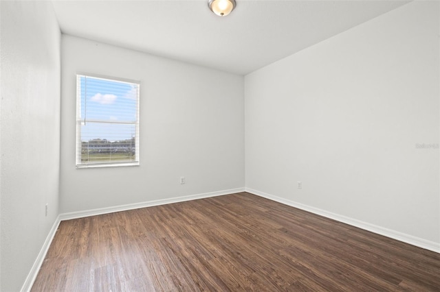 spare room featuring baseboards and dark wood-style floors