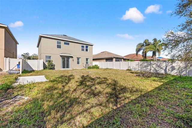 back of house featuring a gate, a fenced backyard, stucco siding, a patio area, and a lawn