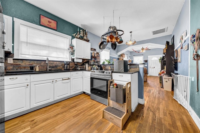 kitchen with stainless steel electric range oven, visible vents, white cabinets, a sink, and a peninsula