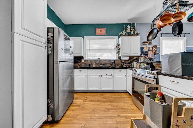 kitchen featuring appliances with stainless steel finishes, light wood-style floors, white cabinets, and a sink