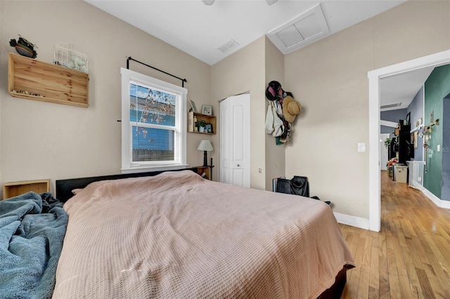 bedroom featuring light wood finished floors, a closet, visible vents, attic access, and baseboards