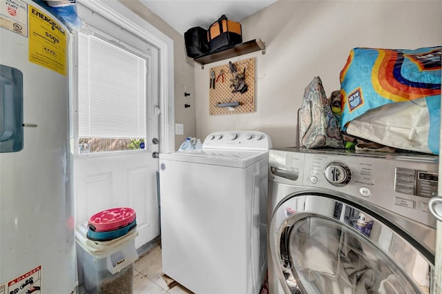 laundry room featuring water heater, laundry area, washing machine and dryer, and light tile patterned floors