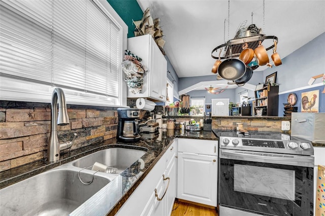 kitchen with a sink, white cabinetry, stainless steel electric range, tasteful backsplash, and dark stone countertops