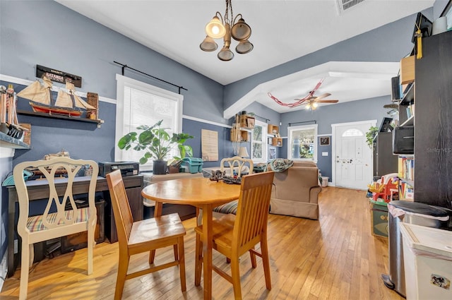 dining space with ceiling fan with notable chandelier, visible vents, and hardwood / wood-style flooring