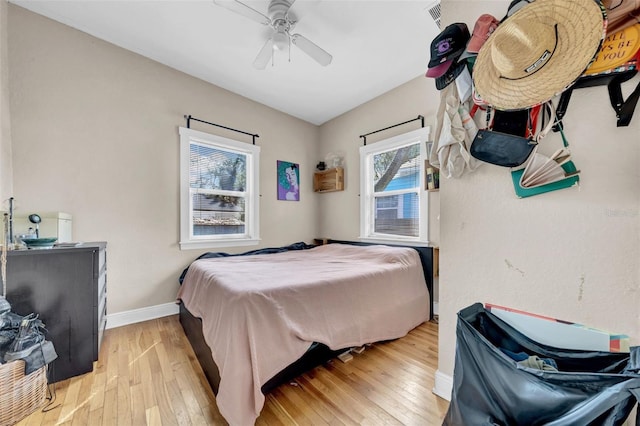 bedroom featuring baseboards, a ceiling fan, visible vents, and light wood-style floors