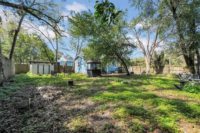 view of yard featuring a storage shed, an outdoor structure, and a fenced backyard