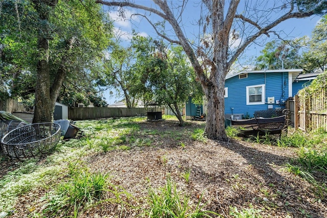 view of yard featuring a fenced backyard, an outdoor structure, and a storage shed