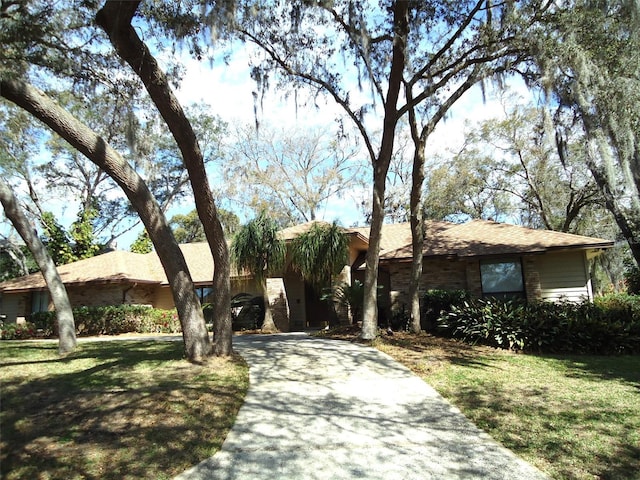 ranch-style home with a front yard, concrete driveway, and brick siding