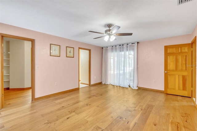 empty room with baseboards, visible vents, a ceiling fan, and light wood finished floors