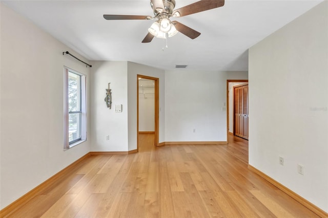 unfurnished room featuring baseboards, light wood-type flooring, visible vents, and ceiling fan