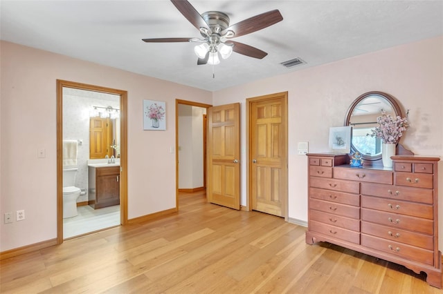 bedroom featuring ensuite bathroom, visible vents, light wood-style flooring, and baseboards