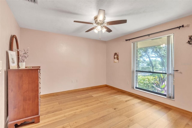 unfurnished room featuring baseboards, a ceiling fan, and light wood-style floors