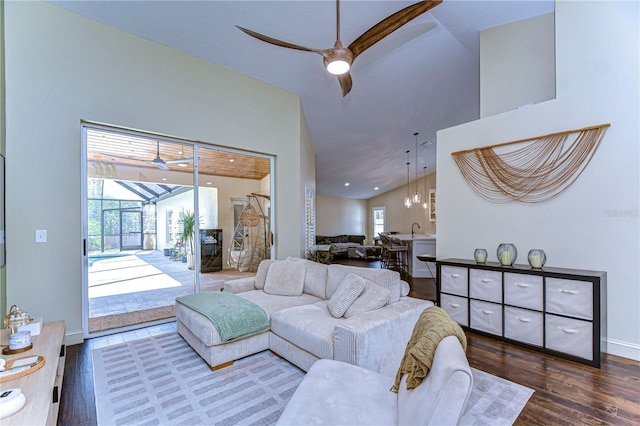 living area featuring a sunroom, ceiling fan, baseboards, and wood finished floors