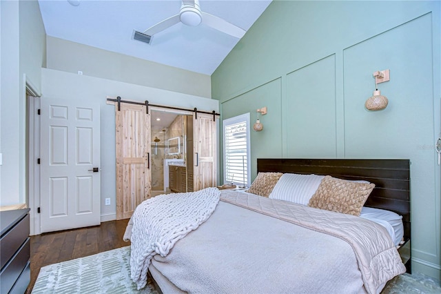 bedroom with lofted ceiling, visible vents, a barn door, ceiling fan, and wood finished floors