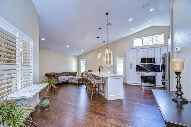 kitchen with dark wood finished floors, stainless steel appliances, light countertops, visible vents, and open floor plan