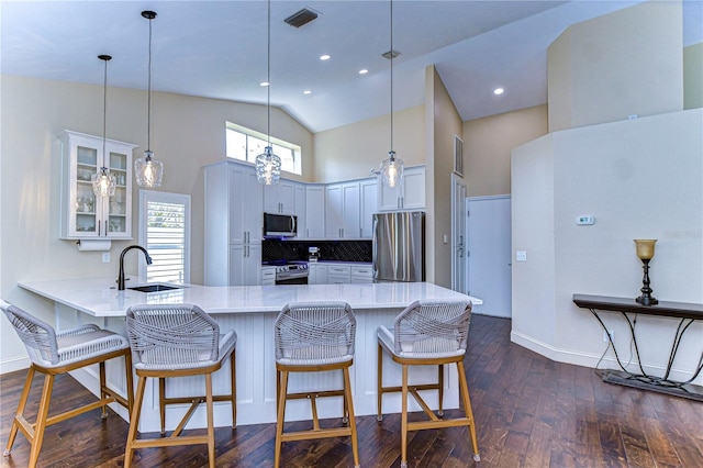 kitchen featuring dark wood finished floors, visible vents, appliances with stainless steel finishes, glass insert cabinets, and a peninsula