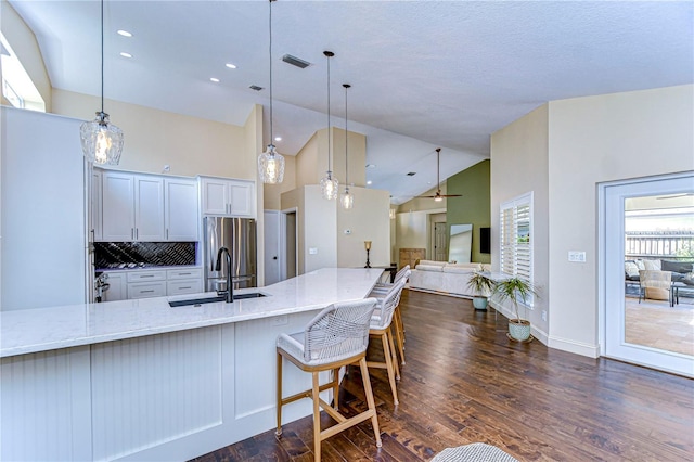 kitchen featuring dark wood finished floors, freestanding refrigerator, white cabinetry, a sink, and light stone countertops