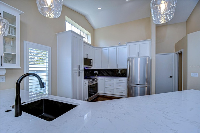 kitchen with appliances with stainless steel finishes, a wealth of natural light, a sink, and light stone counters